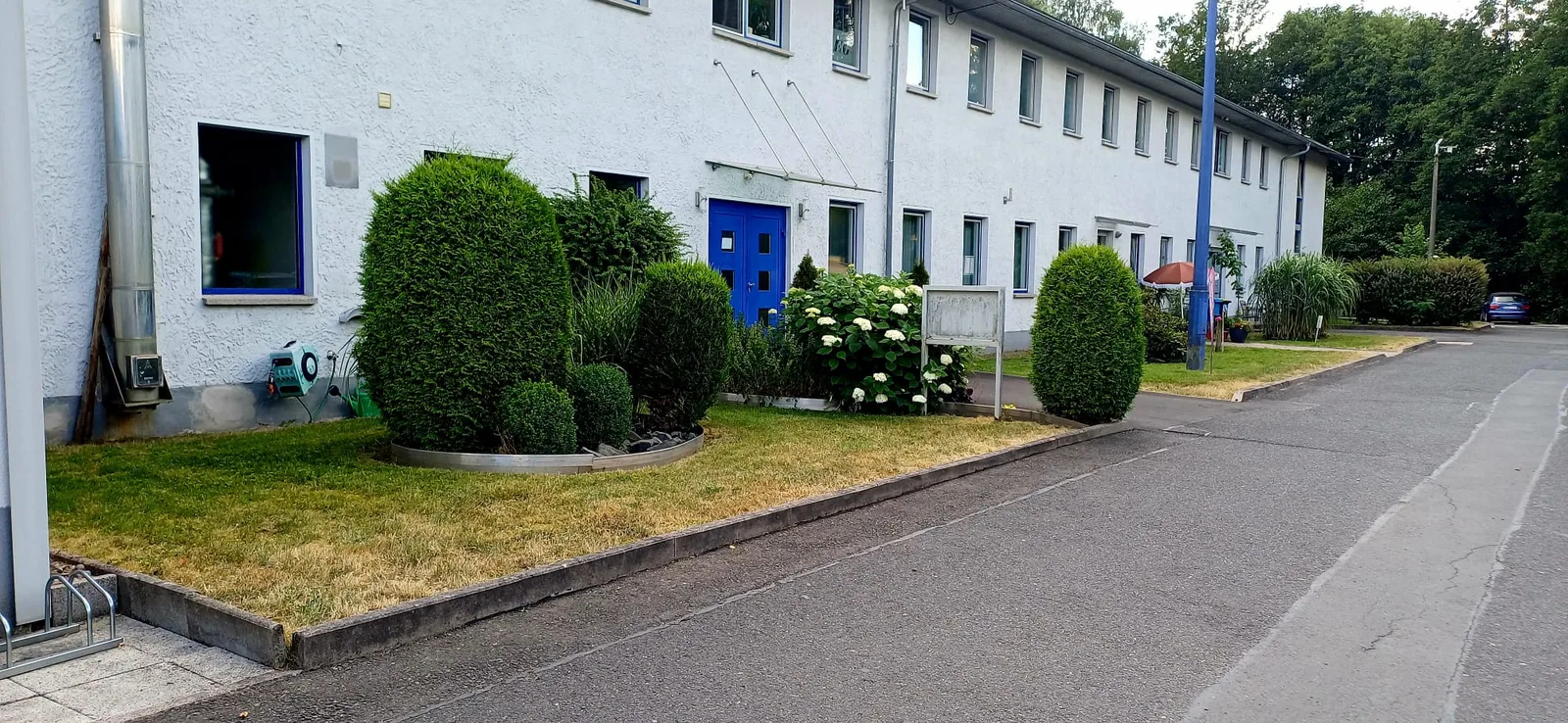 Rasenstreifen, Beet und Stellplatzfläche eines dauerhaft betreuten Objekts