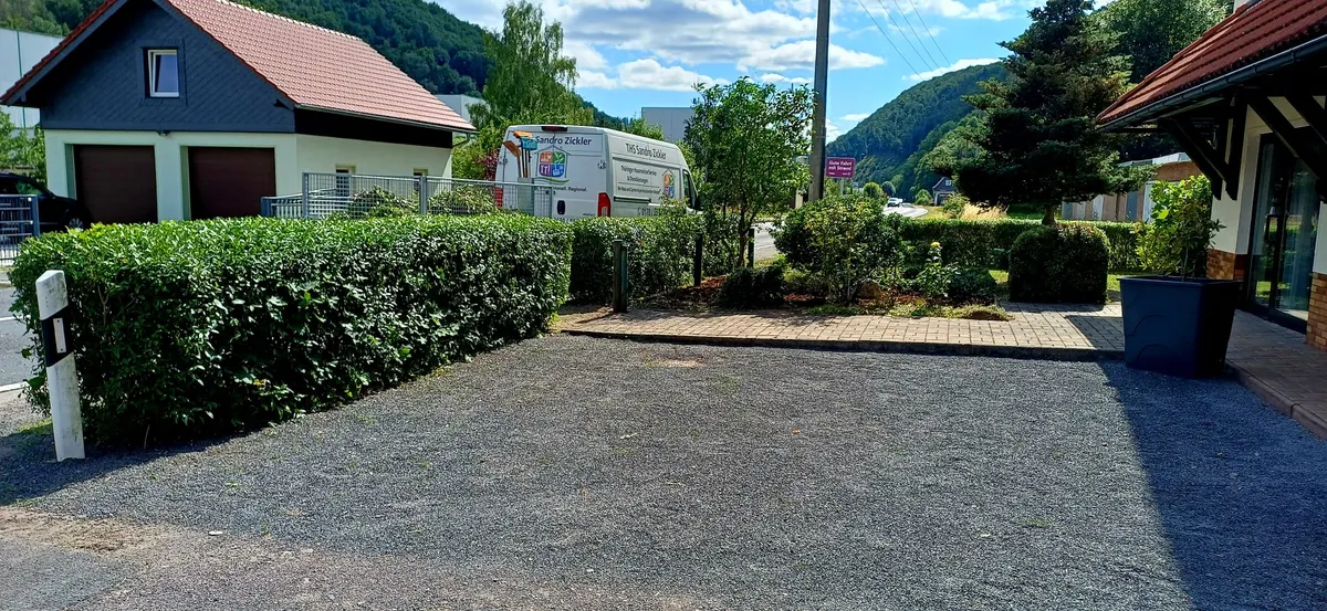 Geschnittene Hecke an einer Stellfläche mit Firmentransporter