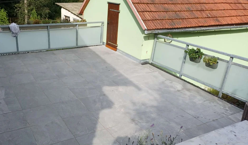 Die fertige Terrasse, neu abgedichtet und mit grauen Feinsteinplatten belegt