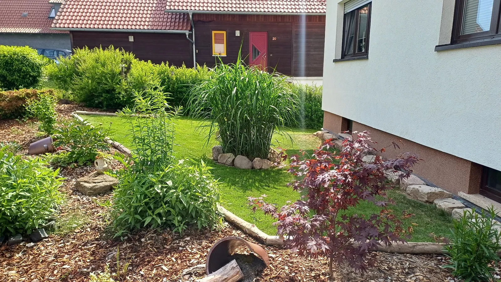 Gepflegter Rasen mit Bepflanzung vor einem Holzhaus
